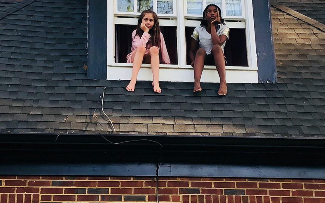 Two girls sitting on the window of dormer loft